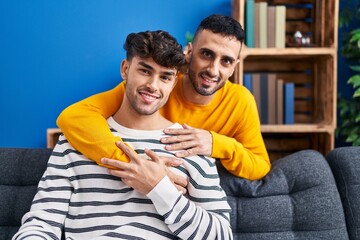 Canvas Print - Two man couple hugging each other sitting on sofa at home