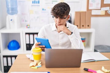 Poster - Young hispanic teenager business worker using touchpad and laptop at office