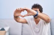 © Krakenimages.com - Young hispanic man doing heart gesture sitting on sofa at home