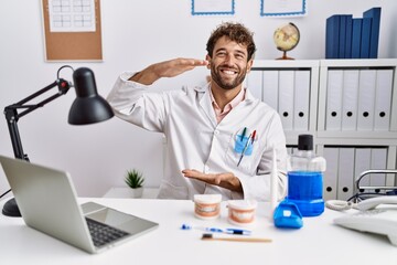 Sticker - Young hispanic dentist man working at medical clinic gesturing with hands showing big and large size sign, measure symbol. smiling looking at the camera. measuring concept.