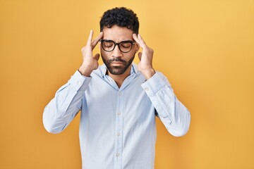 Sticker - Hispanic man with beard standing over yellow background with hand on head for pain in head because stress. suffering migraine.