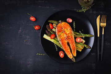 Wall Mural - Roasted salmon garnished with asparagus and tomatoes with herbs. Ketogenic lunch. Keto diet. Top view, above