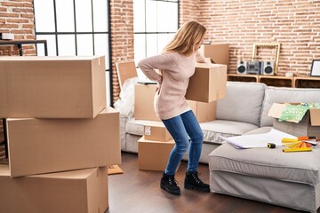 Canvas Print - Young woman suffering for backache holding package at new home