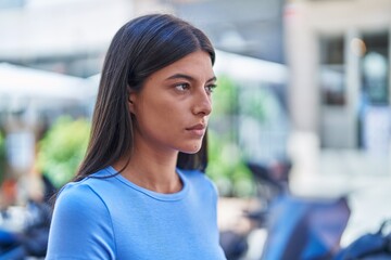 Wall Mural - Young beautiful hispanic woman looking to the side with serious expression at coffee shop terrace