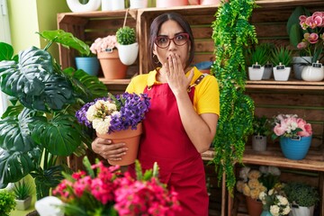 Sticker - Young arab woman working at florist shop holding plant covering mouth with hand, shocked and afraid for mistake. surprised expression