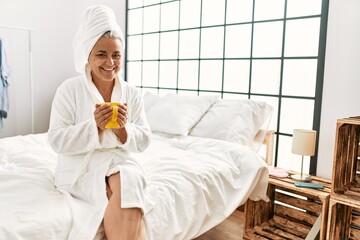 Wall Mural - Middle age grey-haired woman drinking cup of coffee sitting on the bed at bedroom.