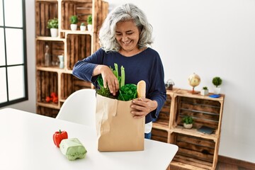 Sticker - Middle age grey-haired woman holding paper bag with groceries standing at home.