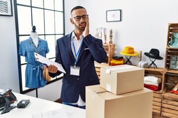 Poster - African american man working as manager at retail boutique touching mouth with hand with painful expression because of toothache or dental illness on teeth. dentist concept.