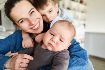 Wall Mural - Happy smiling mother with baby and big brother