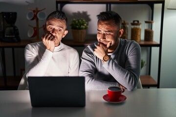 Poster - Homosexual couple using computer laptop thinking worried about a question, concerned and nervous with hand on chin