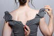 Woman unzips the zipper on the dress. Bunette female rear view with hair knot and earrings in the ears.
