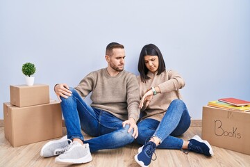 Canvas Print - Young couple moving to a new home checking the time on wrist watch, relaxed and confident