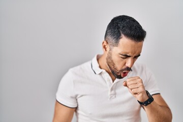 Sticker - Young hispanic man with beard wearing casual clothes over white background feeling unwell and coughing as symptom for cold or bronchitis. health care concept.