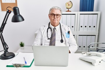 Wall Mural - Senior caucasian man wearing doctor uniform and stethoscope at the clinic with hands together and crossed fingers smiling relaxed and cheerful. success and optimistic