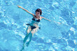 © ALEXEY - An adult brunette woman is bathing in a pool with blue clear water.
