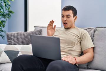 Poster - Young arab man using laptop at home scared and amazed with open mouth for surprise, disbelief face