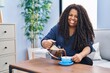 © Krakenimages.com - African american woman pouring coffee on cup sitting on sofa at home