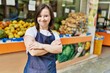 Young down syndrome woman smiling confident wearing apron at fruit store