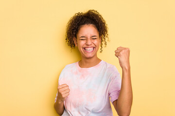 Wall Mural - Young Brazilian curly hair cute woman isolated on yellow background cheering carefree and excited. Victory concept.