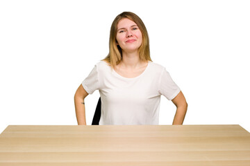 Wall Mural - Young caucasian woman sitting on a chair in a desktop isolated happy, smiling and cheerful.