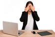 © Asier - Young business asian woman sitting on a table isolated afraid covering eyes with hands.