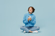 © ViDi Studio - Full body fun young woman wear knitted sweater hold in hand use mobile cell phone look aside on workspace isolated on plain pastel light blue cyan background studio portrait. People lifestyle concept.