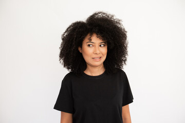 Wall Mural - Dissatisfied young woman showing irritation. Hispanic female model with afro hairstyle and brown eyes in black T-shirt making irritated facial expression. Emotion, dissatisfaction concept