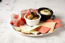 Antipasto Platter With Cheese, Crackers, Prosciutto, Salami And Hummus