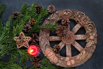 Wall Mural - wiccan altar with Wheel of the year candle, amulet deer, cones, fir branches on dark abstract background. Witchcraft Esoteric Ritual. symbol of Yule, Winter Solstice holiday. top view