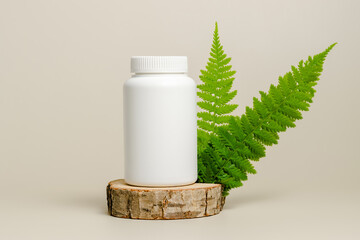 Mockup vitamin bottle on wooden stand with fern leaves, natural bio supplement, herbal medical pills, beige background