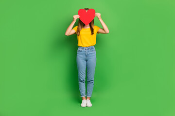 Poster - Full body portrait of young girl arms hold paper heart symbol card cover face isolated on green color background