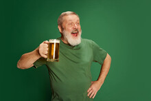 Portrait Of Senior Man In T-shirt Posing With Beer Isolated On Green Background. St Patrick's Day Celebration. Drunk Look