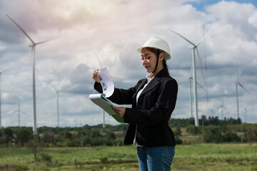 Wall Mural - Asian woman Power engineer are working with wind turbines.Electrical engineer female Renewable Energy power plant Sustainability concept.Professional Expert wind power clean energy farm.