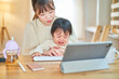 © maru54 - 自宅でタブレットPCを操作する女性と泣く幼児