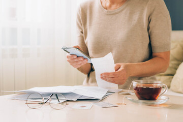 Woman holds phone in her hands for paying bills, receipts of financial checks, budget planning