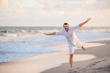 Wall Mural - Young man in white on the beach having fun