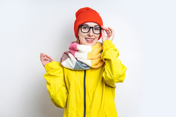 Wall Mural - Smiling young girl in glasses, in a yellow jacket on a light background.