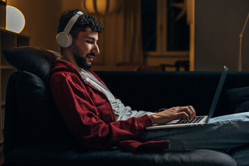 Side view of a man using his laptop at night