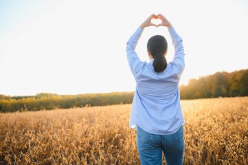 A young female farmer is working in a soybean field at sunset.