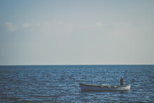 A Lonely Fisherman In A Small Boat At The Open Sea At The Coast Of Naples, Italy 
