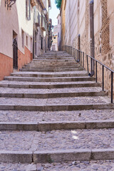 Naklejka na meble Vertical photo of some stairs of a narrow old street in a village. Selective focus.