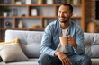 © Prostock-studio - Portrait of handsome african american man resting on couch with cup of coffee