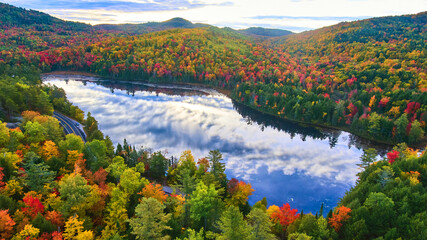 Wall Mural - Morning light shines over reflective lake and stunning mountains of peak fall foliage