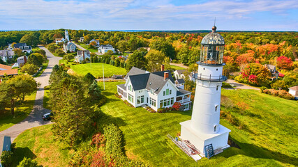 Wall Mural - Pair of white lighthouses on hill with homes and fall foliage