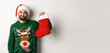 © Mix and Match Studio - Xmas and winter holidays concept. Displeased guy disappointed in gift in Christmas sock, standing upset in Santa hat against white background