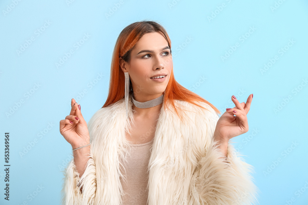 Young transgender woman with beautiful manicure on blue background