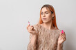 Young transgender woman with pink nail polish on light background