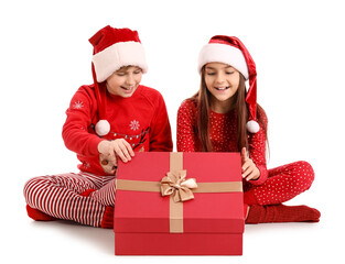 Wall Mural - Little children in Santa hats opening Christmas gift on white background