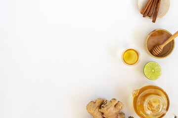 Wall Mural - Top view of a cup of tea with ginger root, lime, cinnamon and teapot on white background. Health drink concept