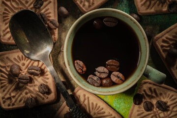 Wall Mural - Still life: a cup of coffee and brown roasted beans stand on a dark green background